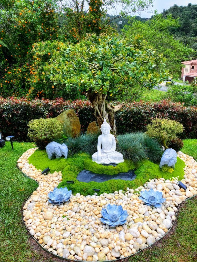 Jardín exterior con un buda ornamental rodeado de piedra decorativa blanca cristal y plantas